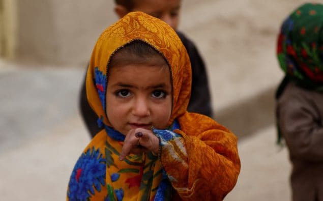 A Pashtun child shows off her marked pinkie finger following polio vaccination.