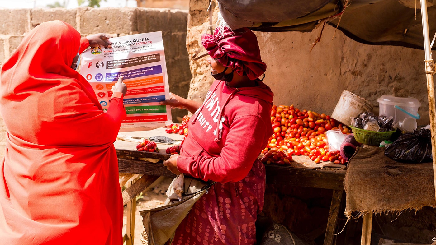 A community volunteer shares information on how to prevent COVID-19 at a market in Nigeria.