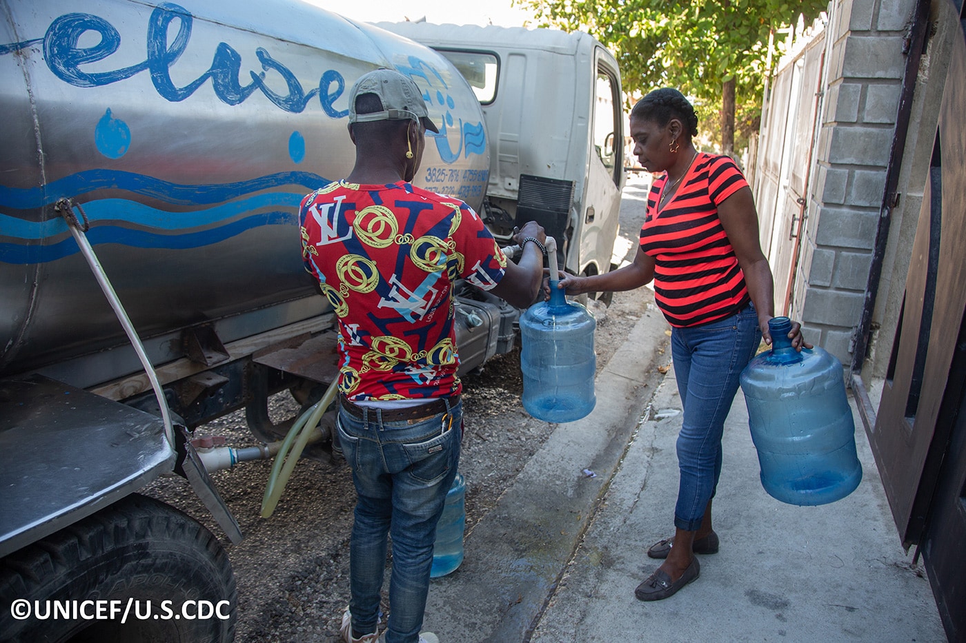 Picture of a man and a woman filling water containers from a mobile tanker.