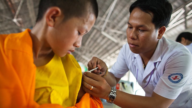 In Vietnam, a male nurse administering flu vaccine to young boy.