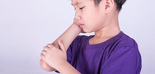 A young boy holds his elbow as if in pain