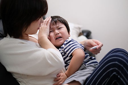 Una madre consuela a su hijo después de tomarle la temperatura