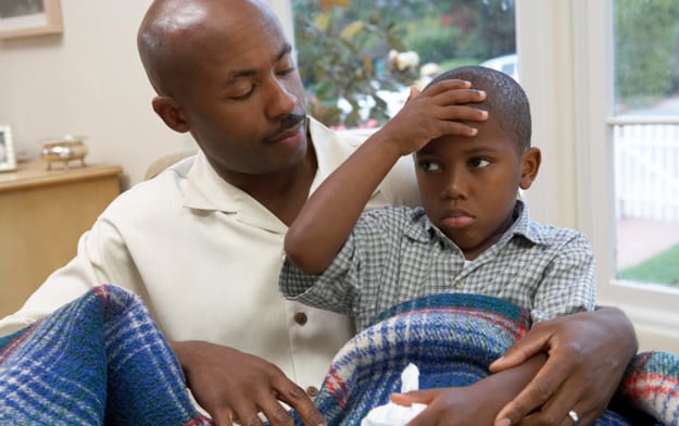 Photo: Son holding his head in pain while sitting on Dad's lap