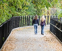 2 women walking on a park path