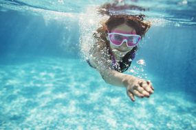 Teenage girl swimming crawl. Shot from underwater.