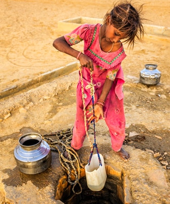 Image of young girl getting water from a well in a plastic container