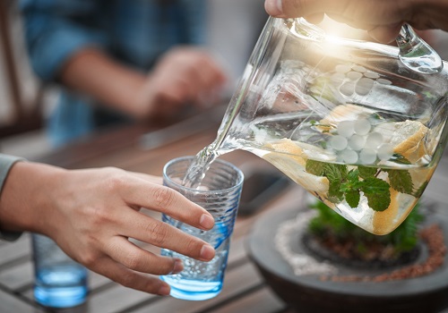 4 خطوات من أجل التحكم بالوزن 14 A pitcher of fruit-infused water filling a glass.