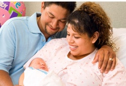 Smiling young Hispanic couple with newborn baby