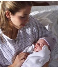 Young mother looking at newborn baby in her arms