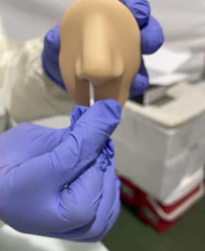 Un administrador de pruebas demuestra cómo se toma una muestra nasal