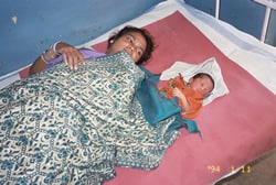 Picture of a mother and her baby in a hospital bed.