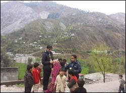 The figure above is a photograph showing public health workers interviewing children in Pakistan.