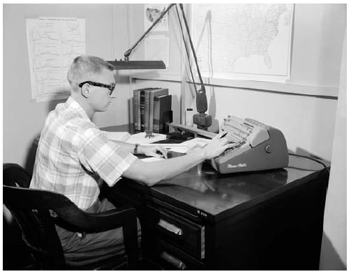 The figure is a photo of a CDC statistician using a MonroMatic desktop calculator in 1958. 