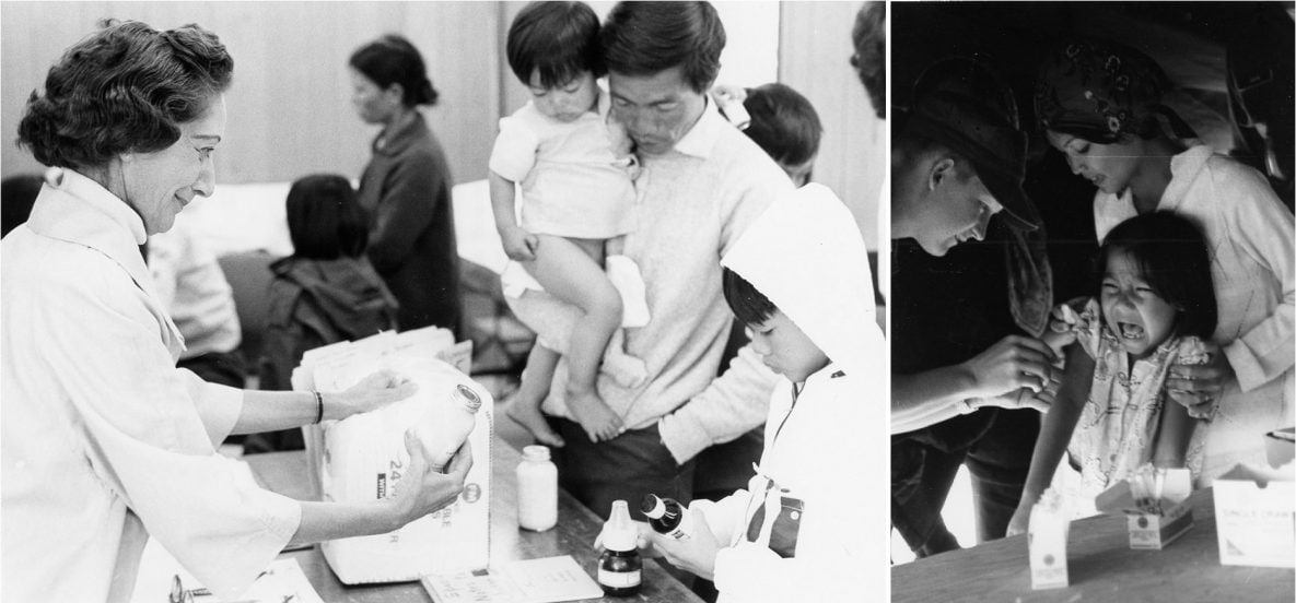 Two photographs taken in 1975 at Camp Pendleton marine base in California. The image on the left shows a Vietnamese man and children standing on one side of a table while a woman administering a medical examination stands on the opposite side.   The photograph on the right features a young refugee anticipating the delivery of a vaccine to her arm. Two women are administering the vaccine and tending to the child.