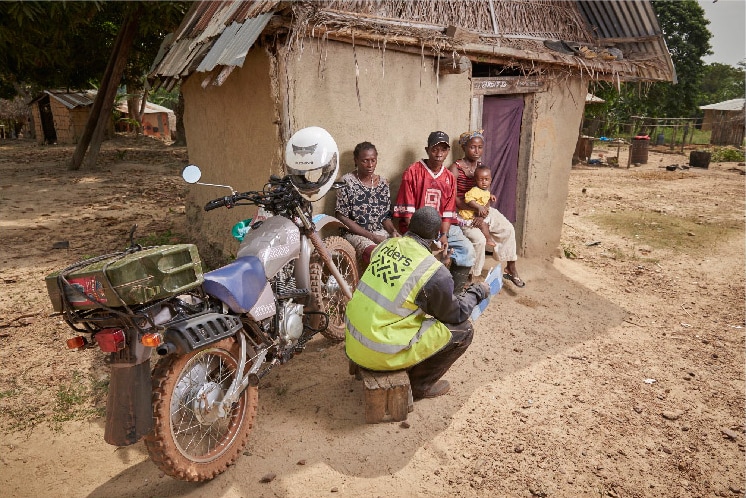 A motorcycle courier consults with an African family.