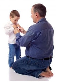 Photo: man helping child with buttons on shirt