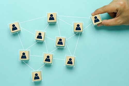 Top view of human resources and recruiting business or team leader concepts. Hand adult Asian man holding of people icon community on wooden cube block.