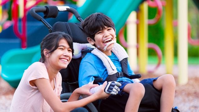 Boy with cerebral palsy sitting next to his sister