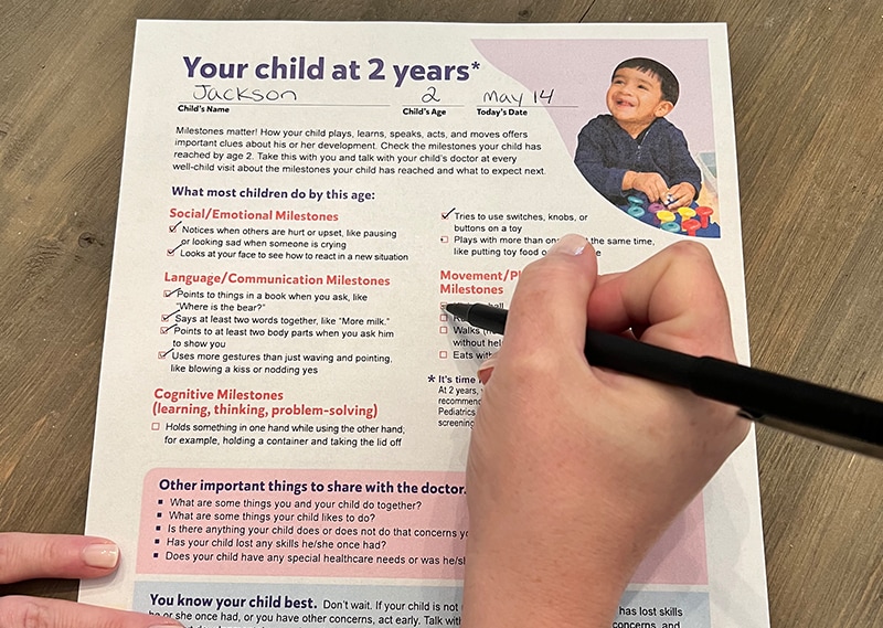 A childcare provider checks items off the Milestone Moments checklist.