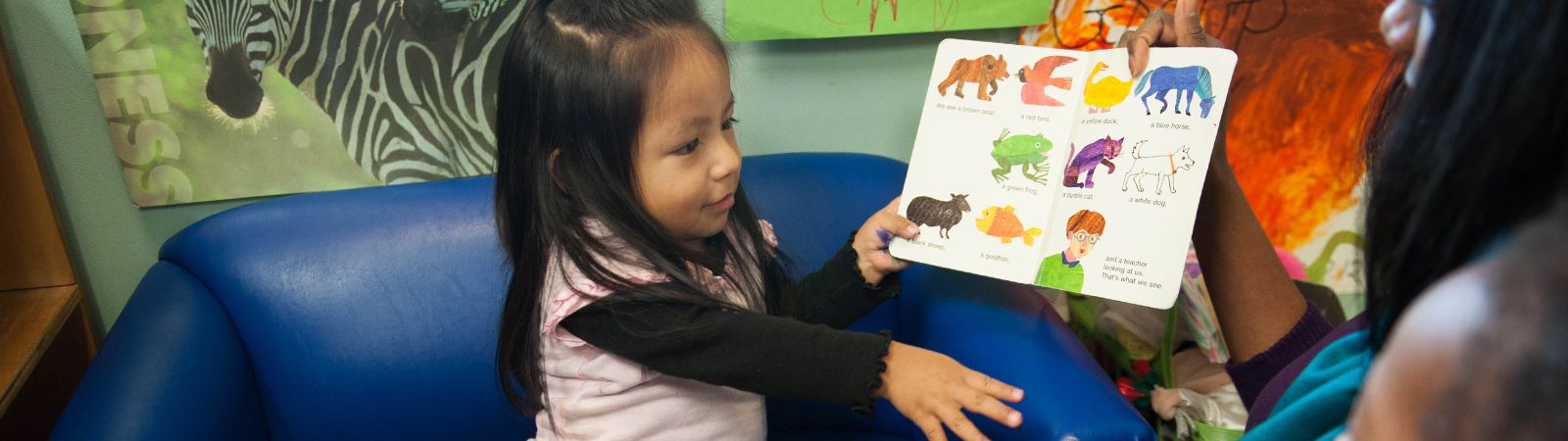 A little girl identifies the animals in a book.