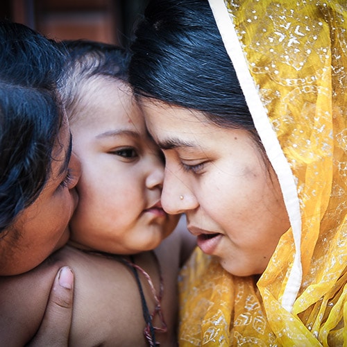A Bangladeshi village mother with her sister cuddling a child.