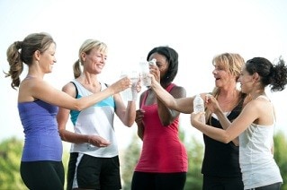 Young women cheers with water bottles after group fitness.