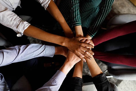 Diverse business team putting their hands on top of each other in a circle.
