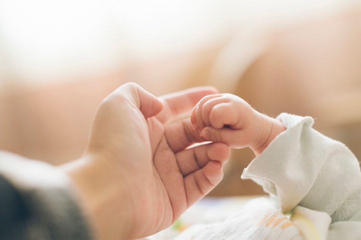 Photo of adult holding infant's hand