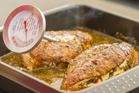 Cooked chicken in a pan with a food thermometer in it.