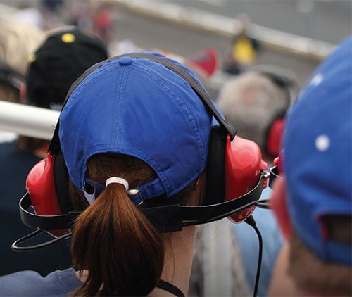 at a car race with noise cancelling headphones