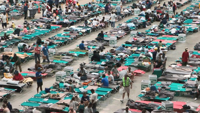 Shelter facility in Austin lined with cots and people.