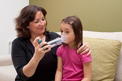 a mother helping her child with an inhaler