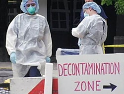 people in hazmat suits standing behind a sign pointing to the decontamination zone