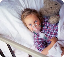Young girl receiving breathing treatment in hospital bed 