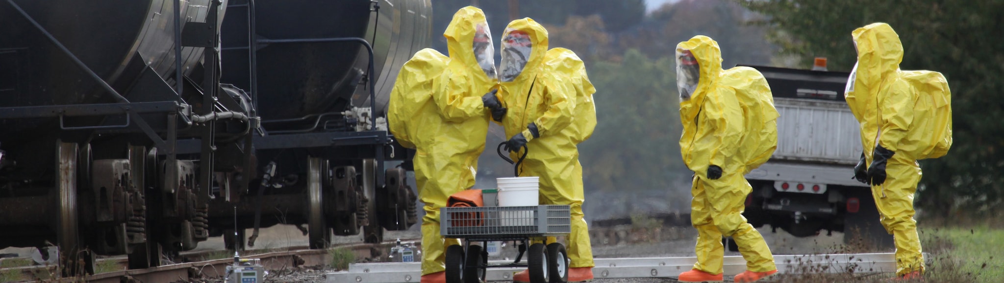 People investigating toxic substances near freight train while wearing hazmat suits