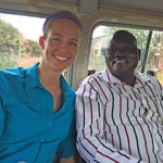 Two smiling epidemiologists sitting on a bus in Uganda