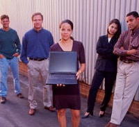Group of men and women standing together around a laptop computer