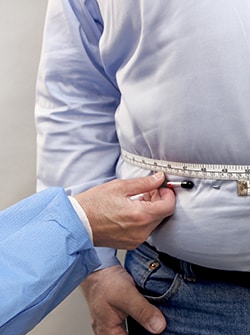 Photo of man's waist being measured with measuring tape