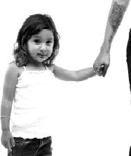 image of young girl holding hand of someone with a tatto on their forearm