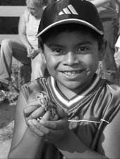 a hispanic boy on a farm holding a small animal