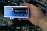 Photo of a Coal Dust Explosibilty Meter (CDEM). Held within a person’s hand and in a mine, demonstrating the real-time operability of the CDEM. The CDEM is indicating Green, Test Complete.