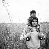 Man in crop field with young boy on his shoulders.