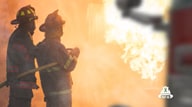 Opening screen of video showing two firefighters pointing a hose at a fire and smoke.