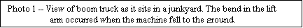 Text Box: Photo 1 -- View of boom truck as it sits in a junkyard. The bend in the lift arm occurred when the machine fell to the ground.