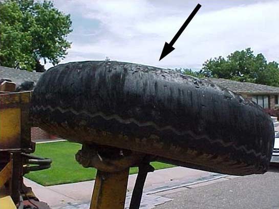 Photo #14:  Right rear-steer tire showing missing tread and chunks of rubber missing from outside of tire.