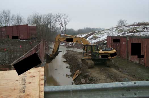 Picture of track hoe used to pull concrete away from worker.