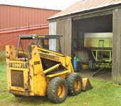 Skid-steer loader, grain wagon, and machine shed.