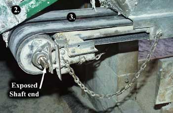 Photo 1 &ndash; View of 12 inch (30cm) wide horizontal conveyor belt that feeds the feed bunk, showing the exposed end of the shaft at waist level.