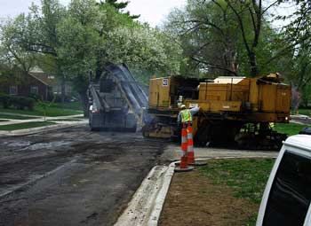 Milling machine discharging asphalt residue into waiting dump truck.