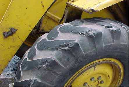 Photo 9.  Left front-drive tire.  Note missing tread and chunks of rubber.